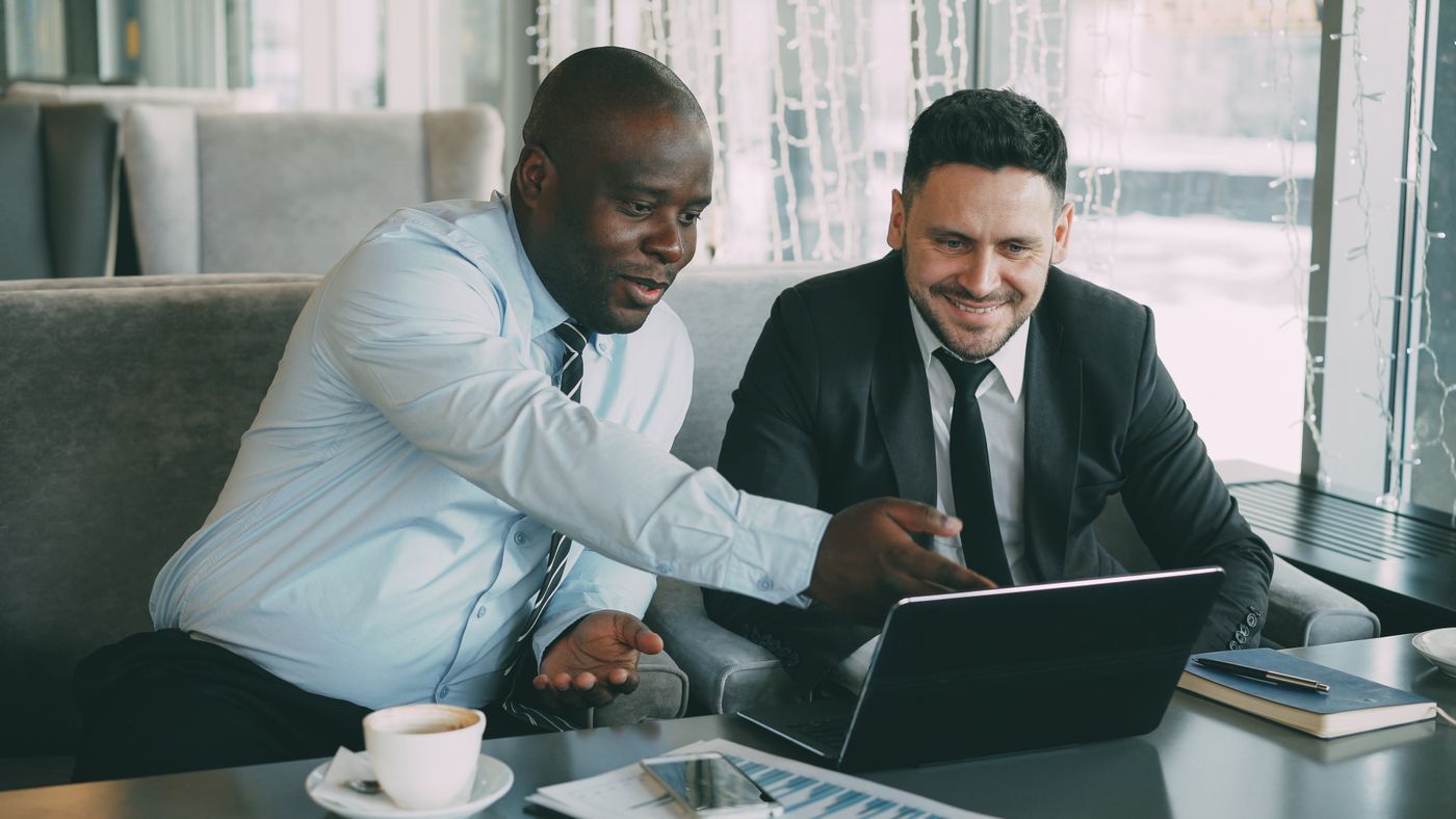 Two colleagues looking at a laptop together over coffee